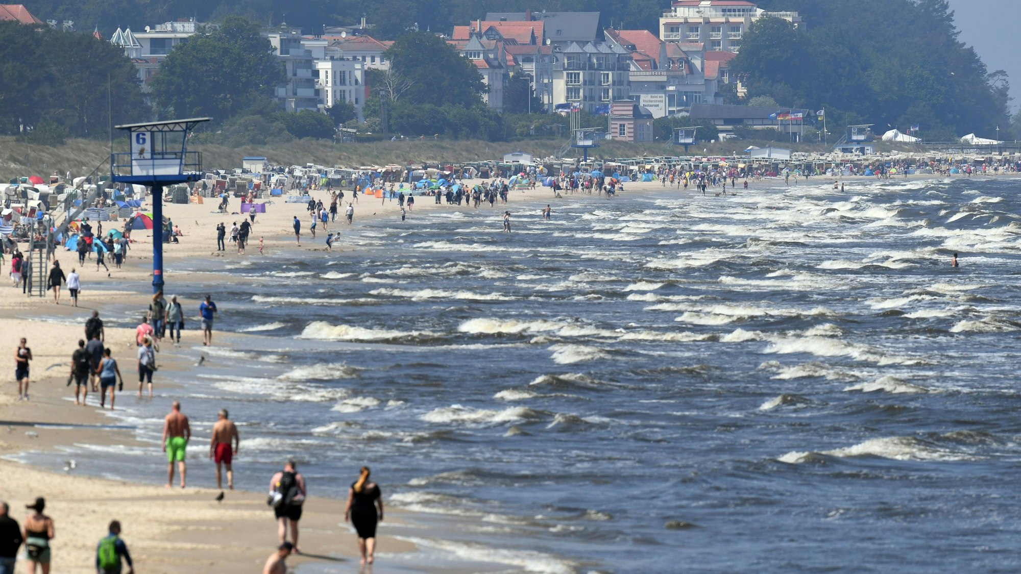 ARCHIV - 13.06.2020, Mecklenburg-Vorpommern, Heringsdorf: Touristen spazieren am Strand an der Ostsee auf der Insel Usedom entlang. Millionen Urlauber in Deutschland fahren jedes Jahr ans Meer. Doch Küste ist nicht gleich Küste. Wer es mild und romantisch mag, bevorzugt die Ostsee. Wilder und rauer geht es hingegen an der Nordsee zu. (zu dpa "Nordsee vs. Ostsee - Was Urlauber an die Küsten zieht") Foto: Stefan Sauer/dpa-Zentralbild/dpa +++ dpa-Bildfunk +++