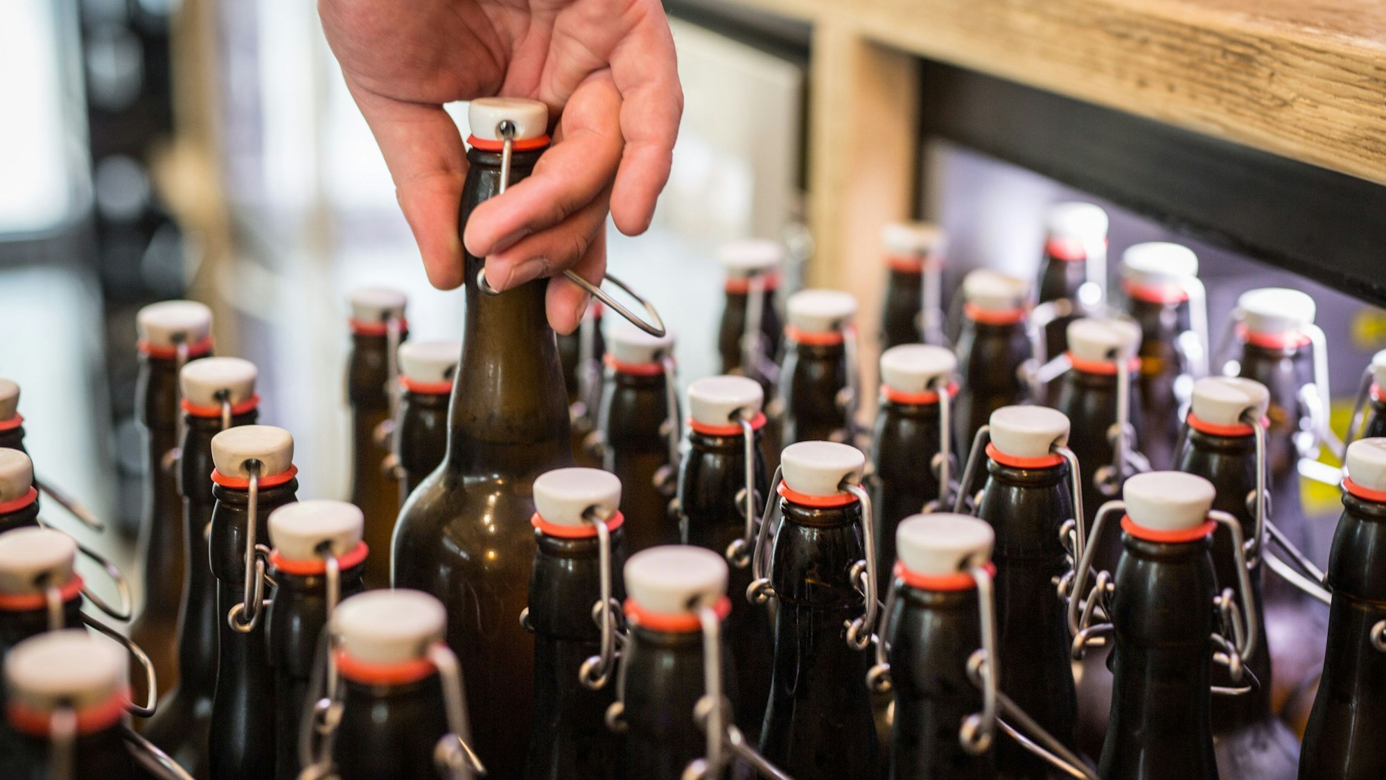 Eine Hand nimmt aus einer Menge von Bierflaschen eine heraus.