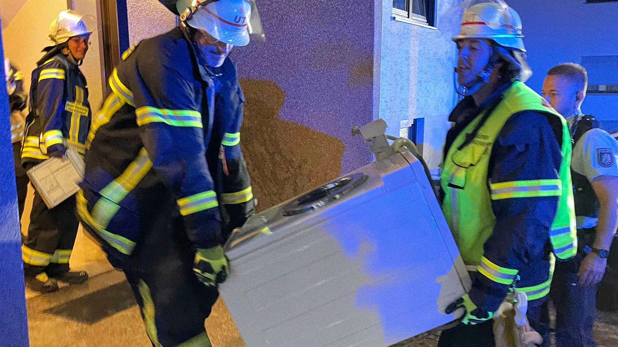 Zwei Feuerwehrleute tragen eine Waschmaschine