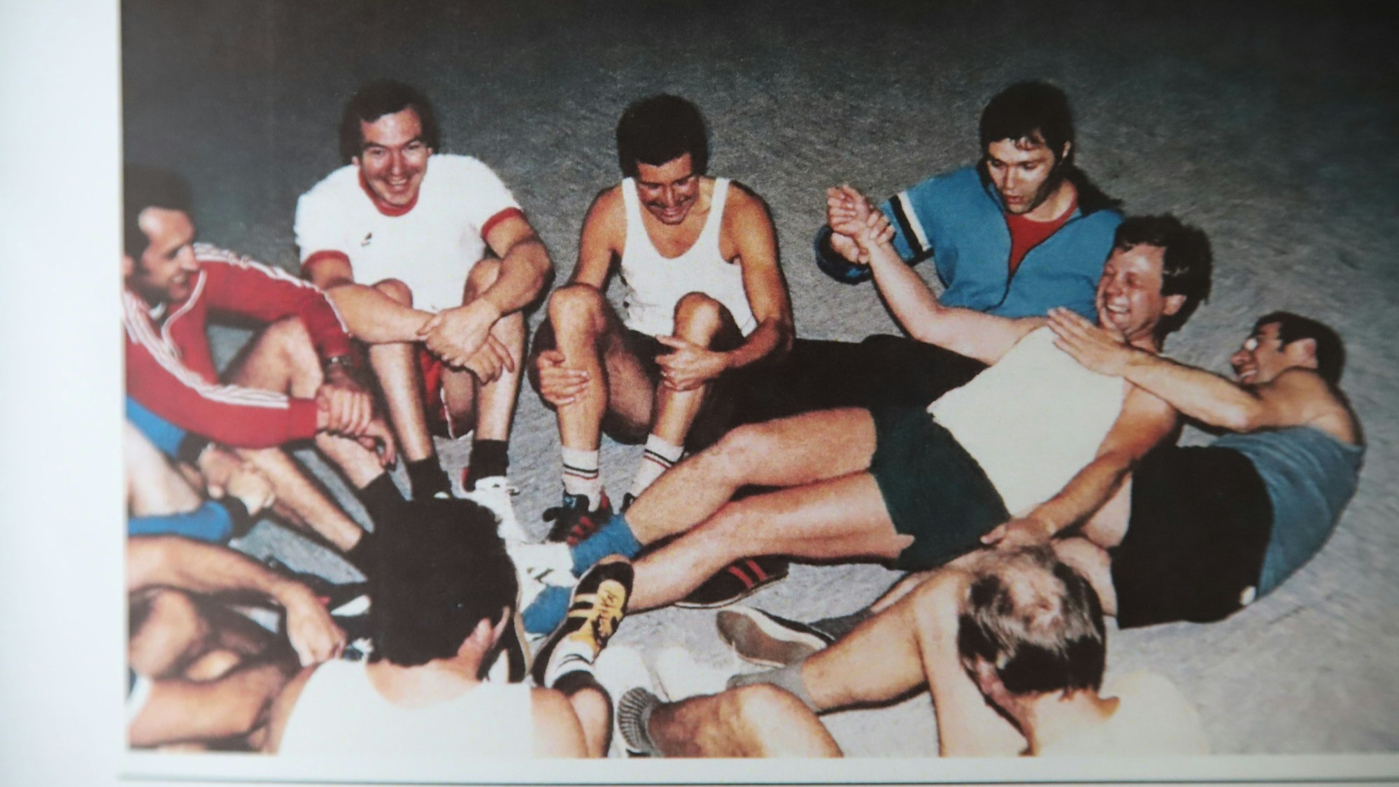 Die Mitglieder des Männerturnens, das es von 1976 bis 1986 gab. Eine Gruppe Männern sitzt in einem Kreis auf dem Boden.