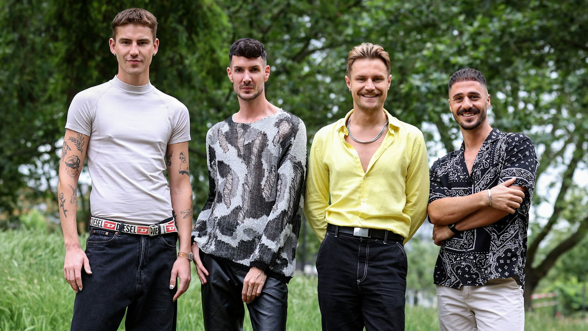 Bast Spädt, Kevin Schäfer, Aaron Königs und Valdi Gunjic stehen im Park nebeneinander und lachen in die Kamera.