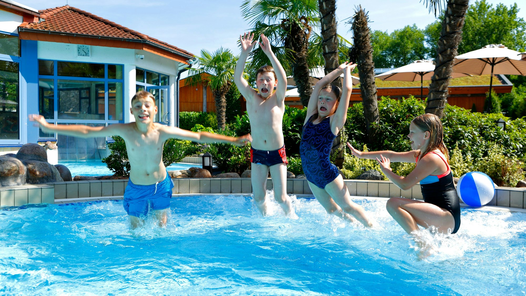 Vier Kinder springen in ein Schwimmbecken.