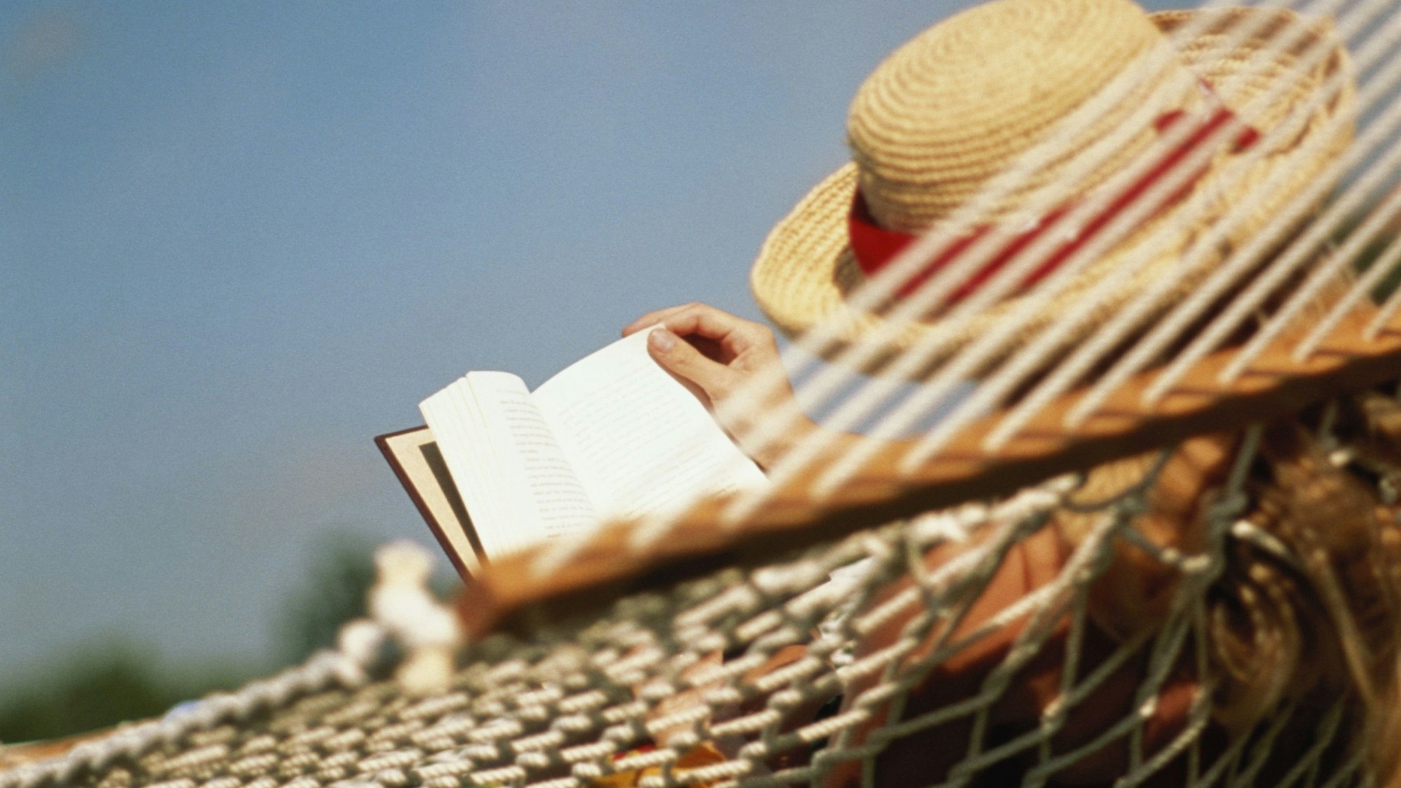 Eine Frau liest in einer Hängematte (Symbolbild)