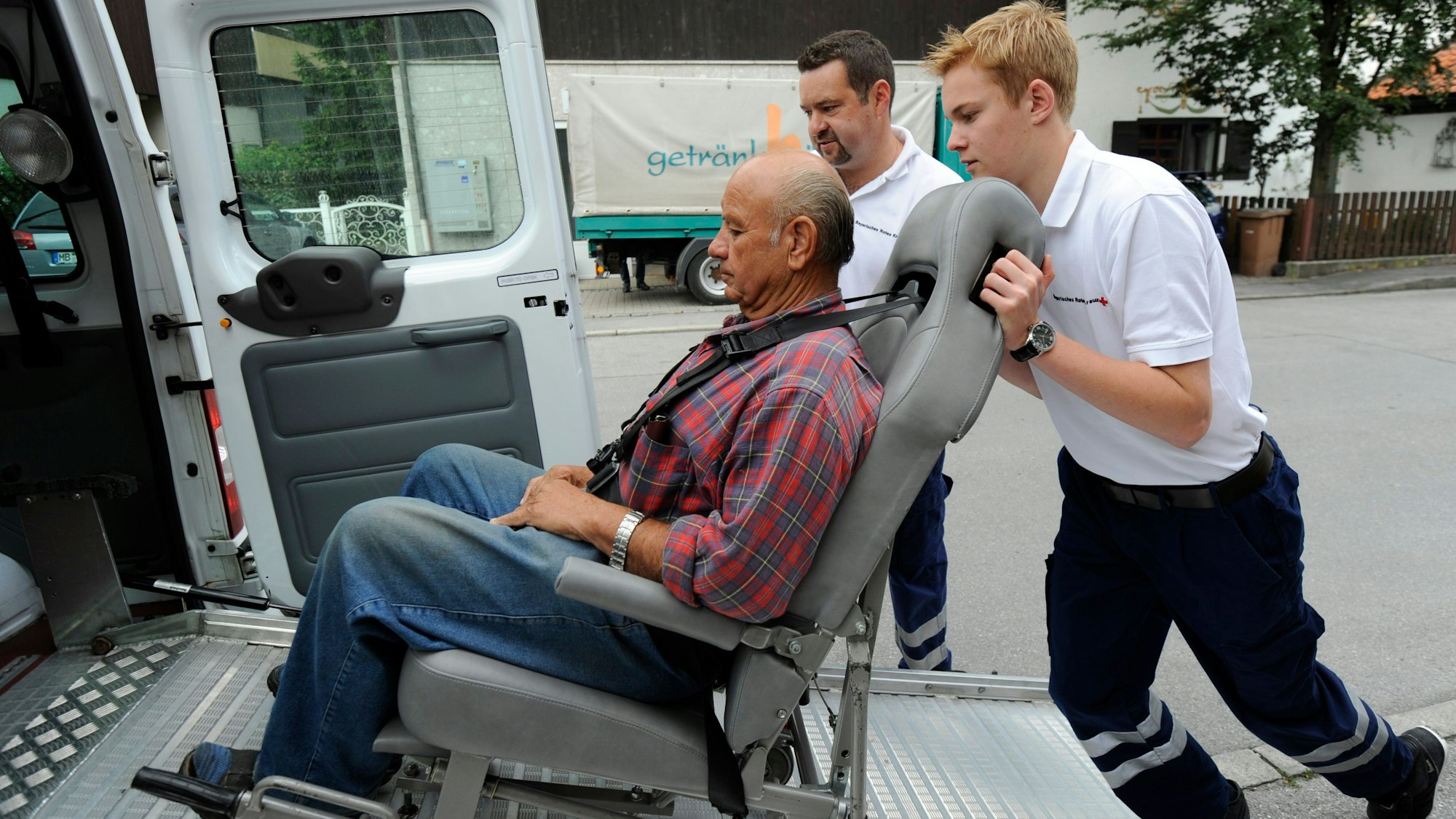 Ein Freiwilligendienstler übt, wie man einen Gehbinderten Menschen in einen Transporter schiebt.