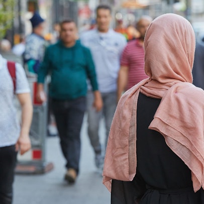 Eine deutsche Konvertitin mit Kopftuch steht im Stadtteil St. Georg auf dem Bürgersteig.