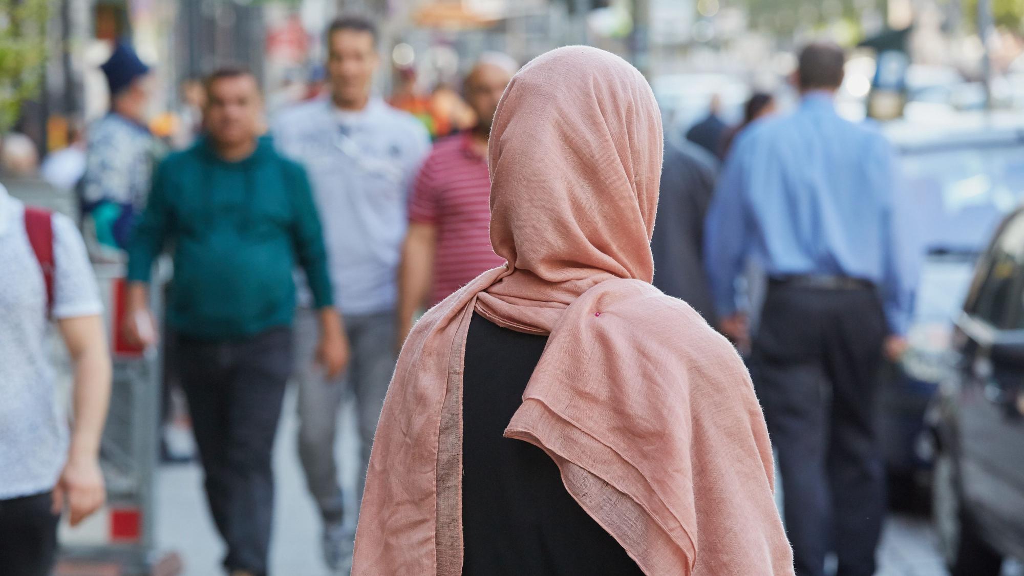 Eine deutsche Konvertitin mit Kopftuch steht im Stadtteil St. Georg auf dem Bürgersteig.