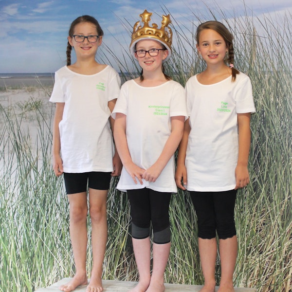 Das Foto zeigt drei Mädchen im weißen T-Shirts, eines davon mit einer Krone auf dem Kopf.