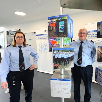 Eine Polizeibeamtin und ihr Kollegen stehen in Uniform zwischen den Tafeln einer Ausstellung.