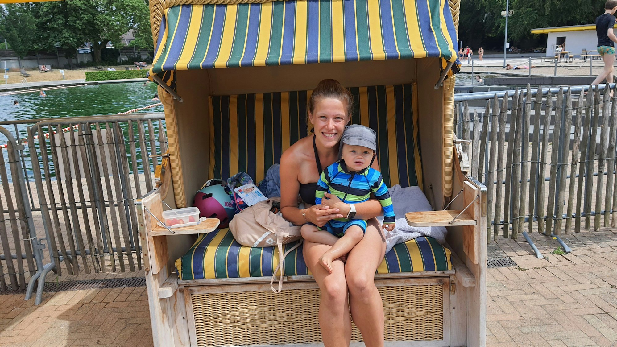 Eine Mutter und ihr Sohn sitzen im Strandkorb vor dem Schwimmbecken.