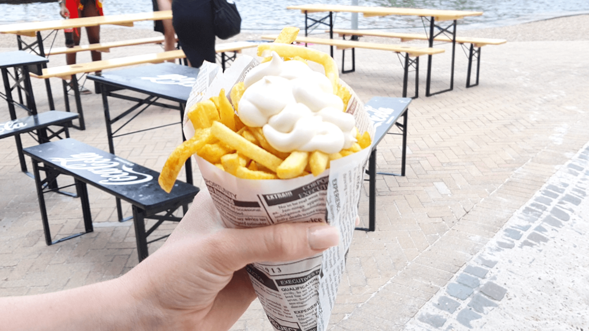 Eine Tüte Pommes mit Mayo wird ins Bild gehalten.