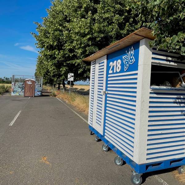 An einer Straße steht ein blau-weiß gestreiftes Häuschen.