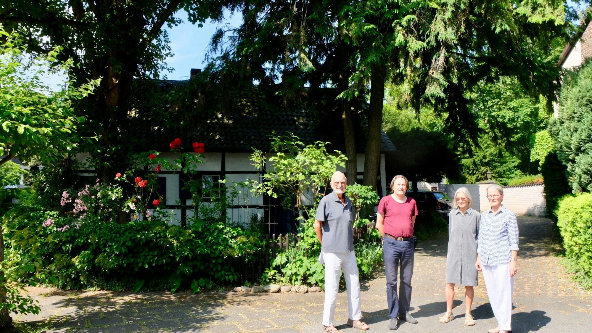 Vier Personen stehen vor einem pittoresken Fachwerkhäuschen.