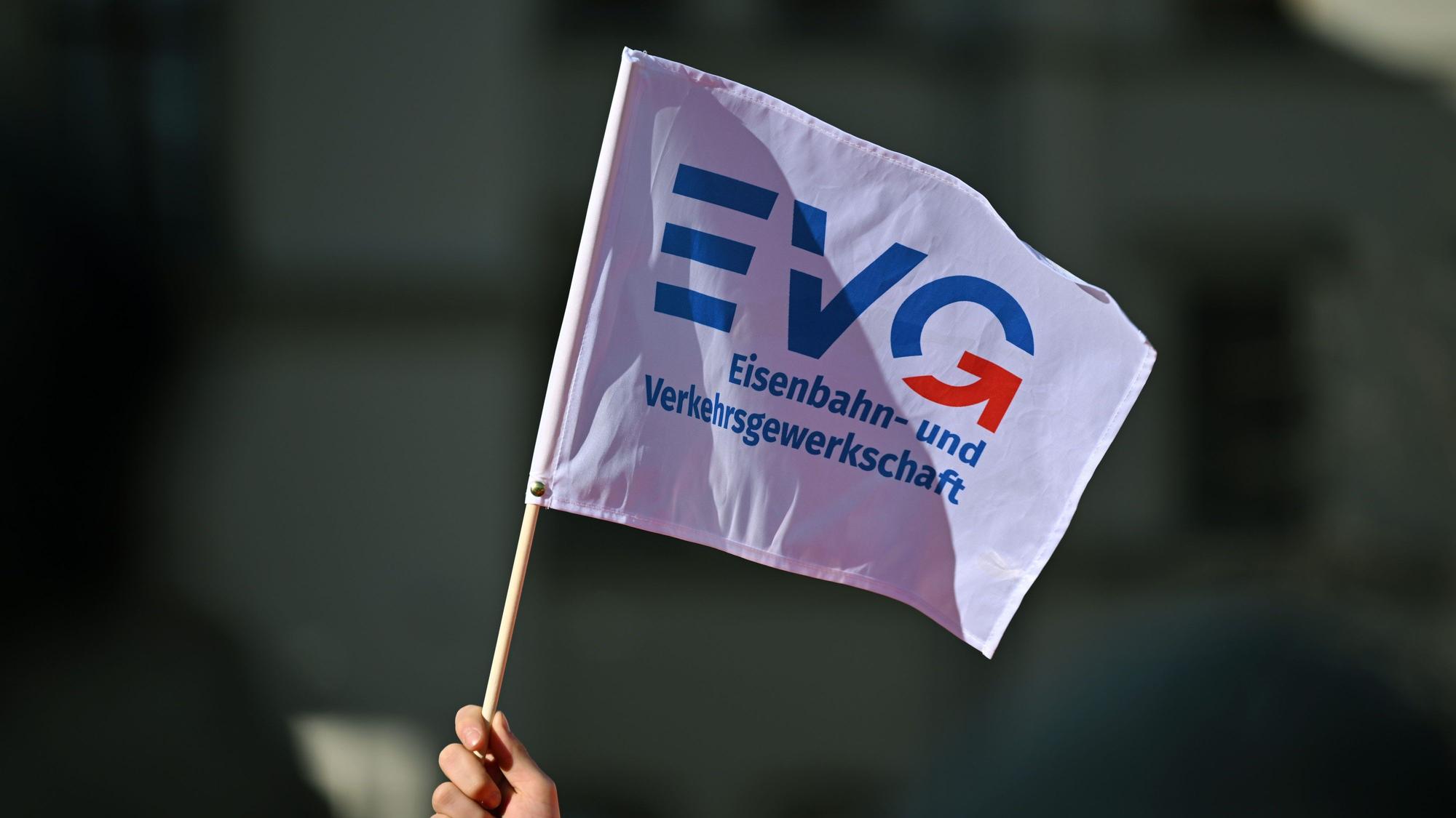 Ein Teilnehmer am Warnstreik vor dem Erfurter Hauptbahnhof schwenkt ein Fähnchen der Eisenbahn- und Verkehrsgewerkschaft (EVG).