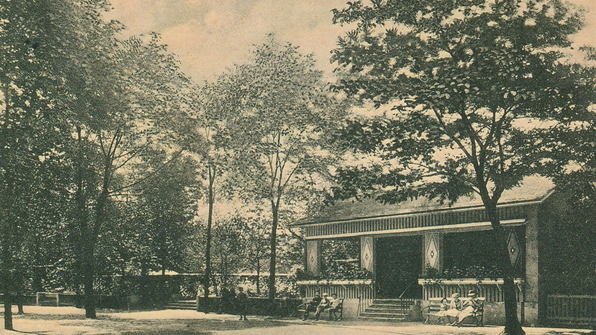 Rechts eine Art Vereinshaus, darum Bäume