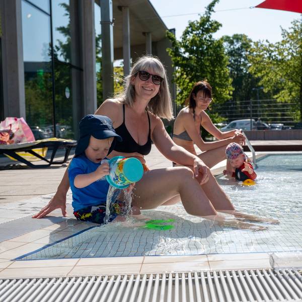 Eine Mutter und ihr Sohn sitzen am Rand des Kinderbeckens im Ossendorfbad.