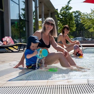 Eine Mutter und ihr Sohn sitzen am Rand des Kinderbeckens im Ossendorfbad.