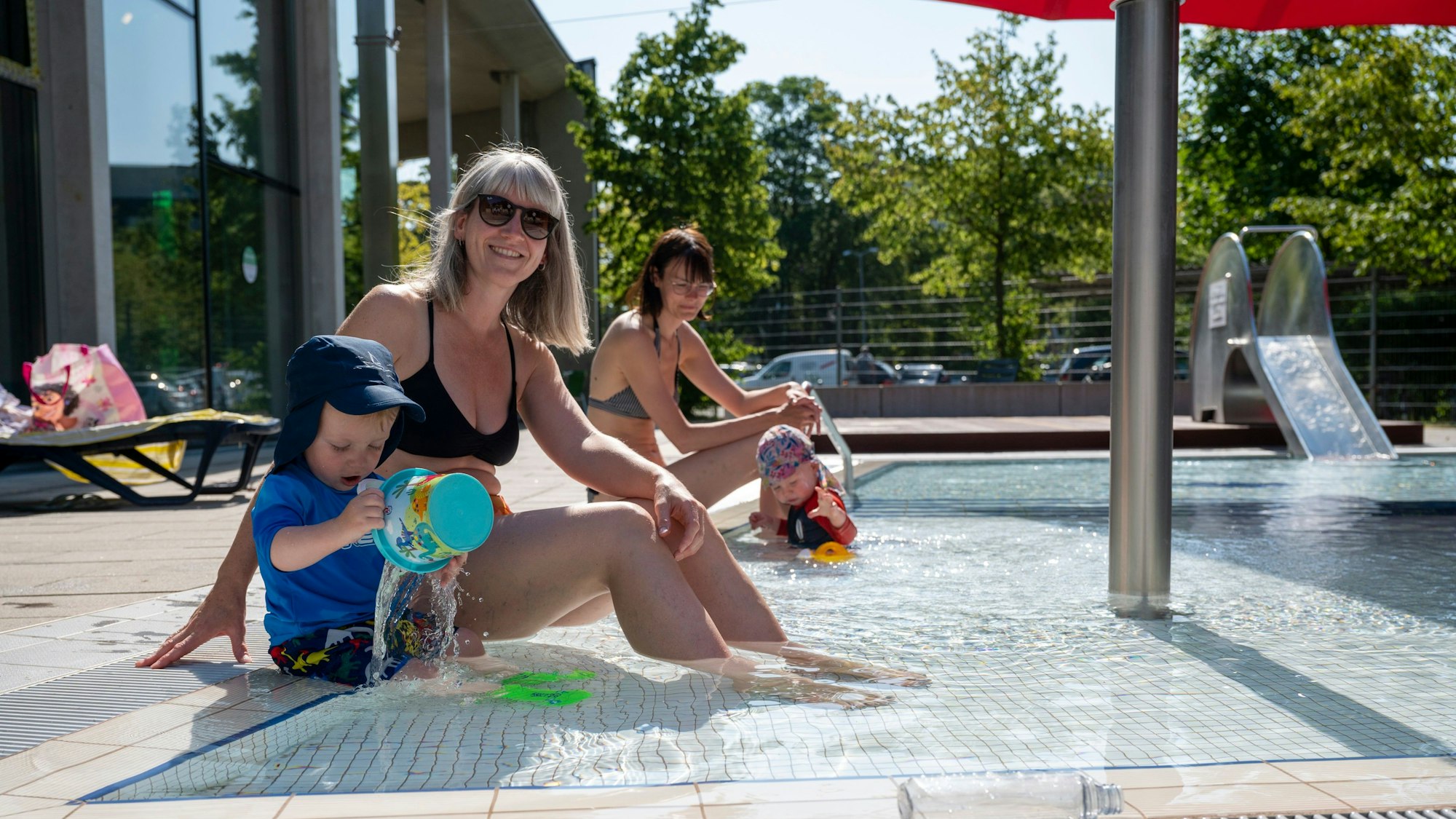 Eine Mutter und ihr Sohn sitzen am Rand des Kinderbeckens im Ossendorfbad.