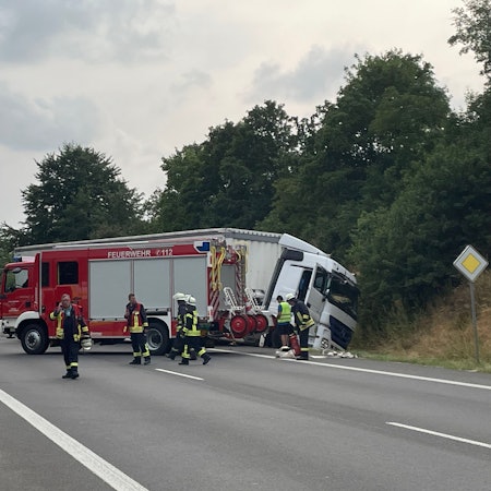 Ein Lkw liegt im Graben. Einsatzkräfte der Feuerwehr sind mit Rettungsarbeiten beschäftigt und sichern die Einsatzstelle.