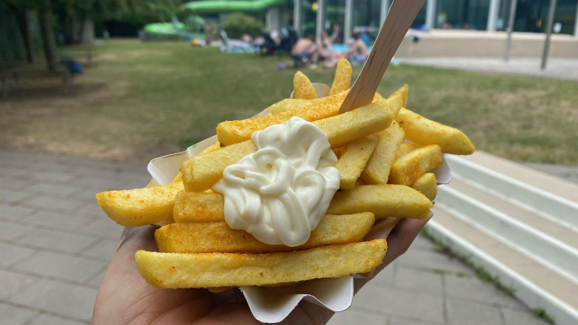 Eine Schale Pommes mit Mayo vor dem Hintergrund des Ossendorfbads.