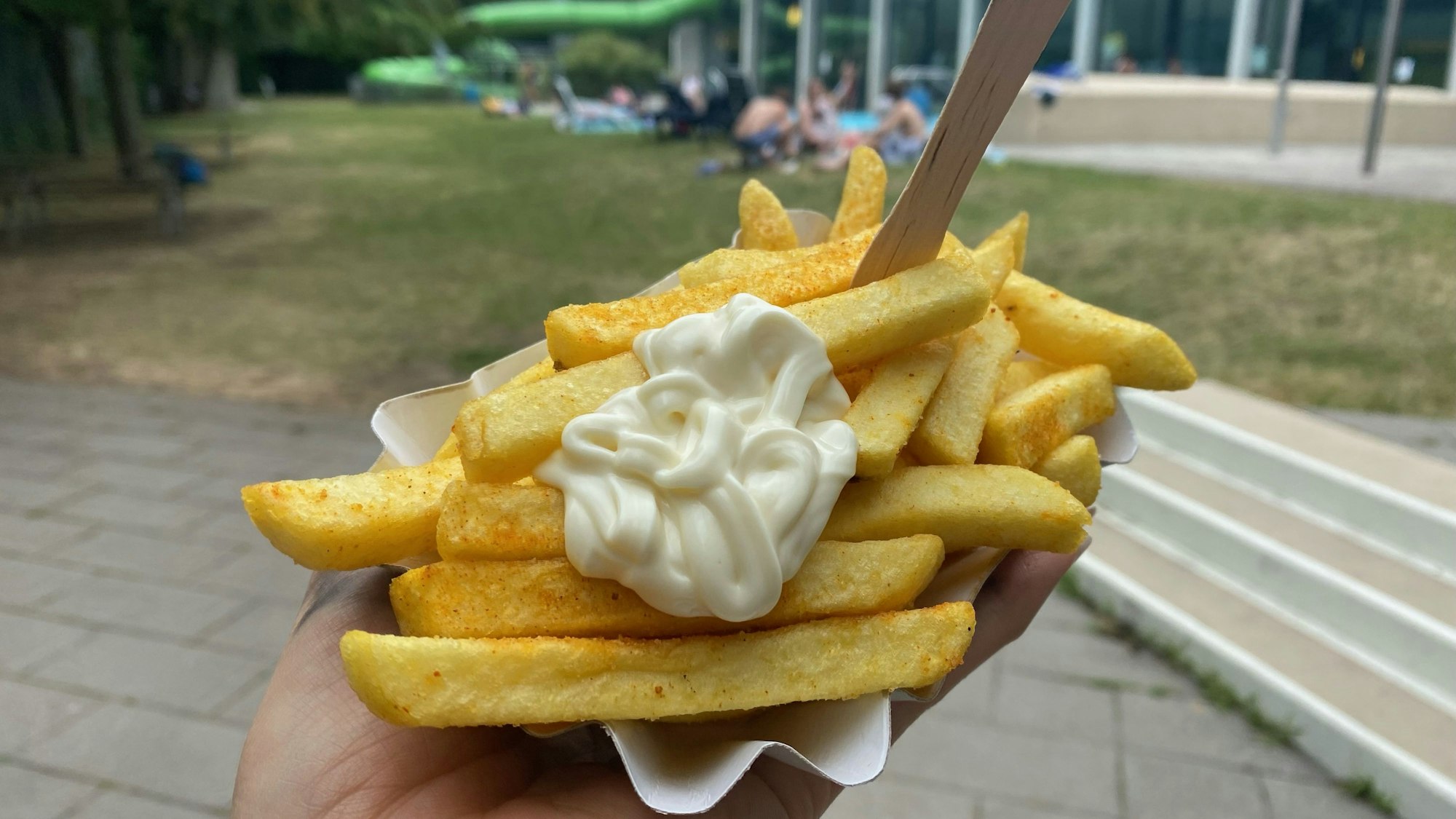 Eine Schale Pommes mit Mayo vor dem Hintergrund des Ossendorfbads.