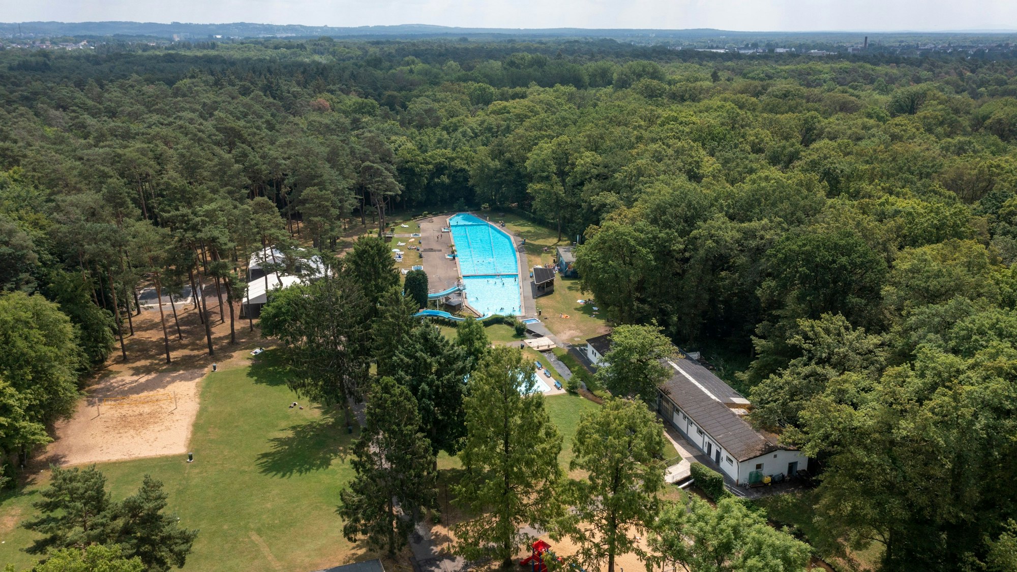 Eine Luftaufnahme zeigt das Kölner Waldbad von oben, mitten im Wald.