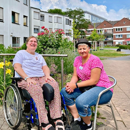 Anette im Rollstuhl, Steffi auf einem Stuhl daneben bei gutem Wetter