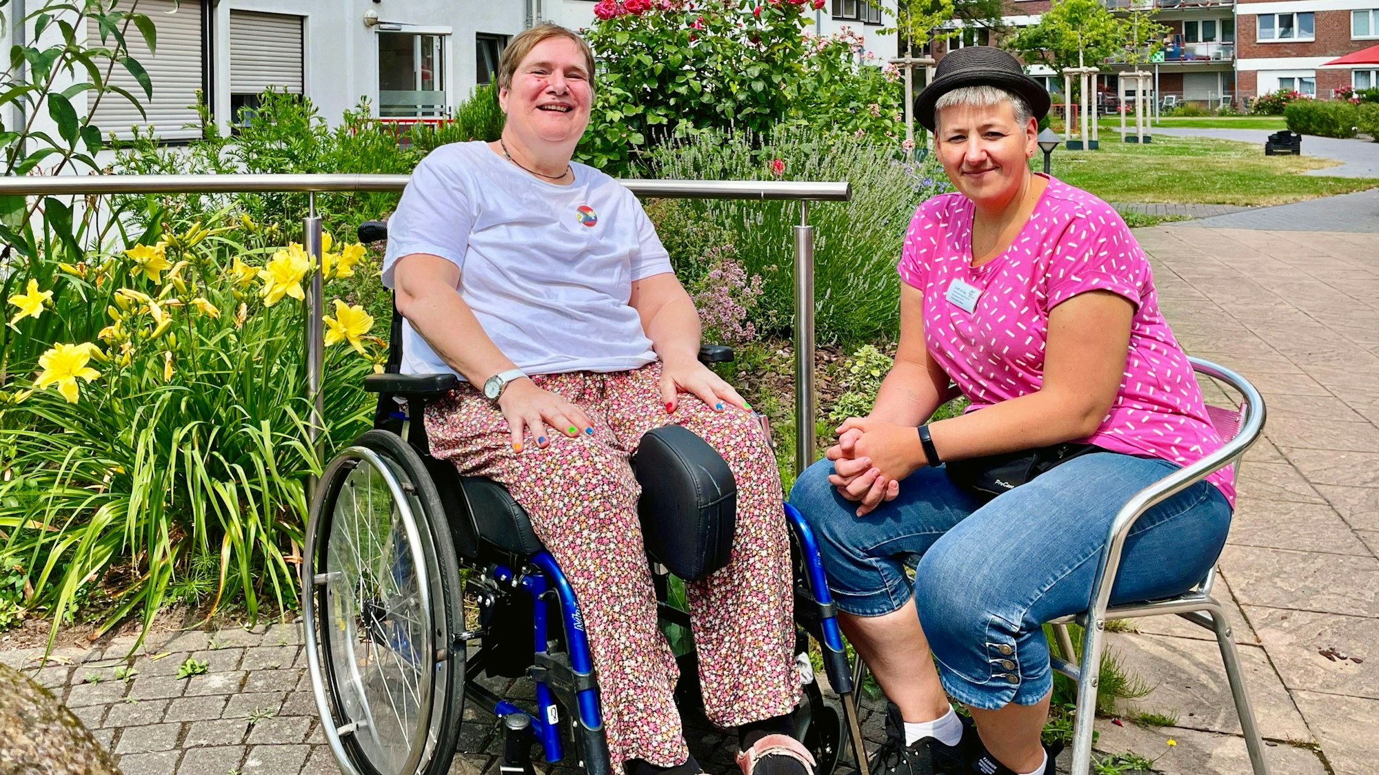 Anette im Rollstuhl, Steffi auf einem Stuhl daneben bei gutem Wetter