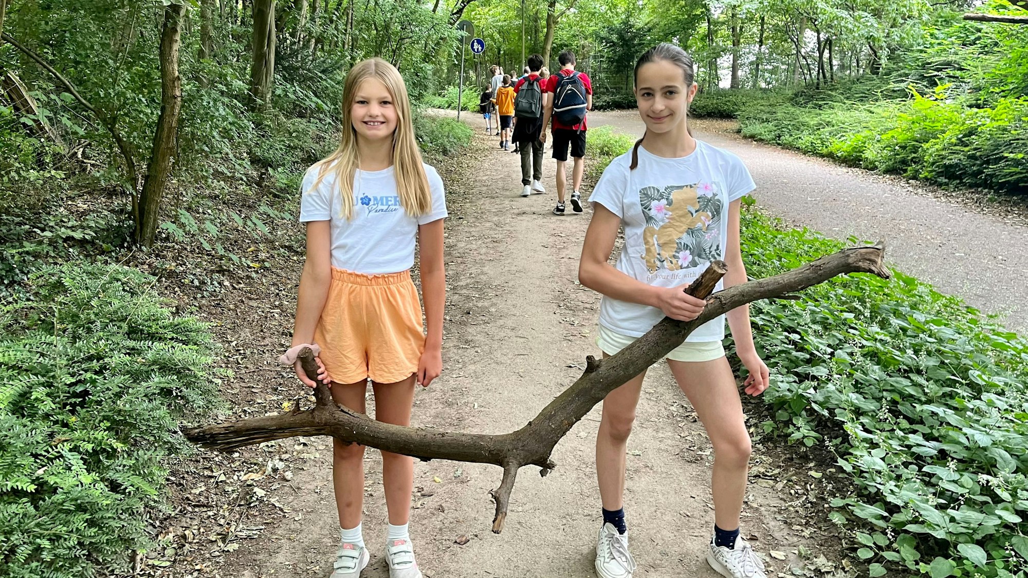 Zwei Mädchen mit einem großen Ast.