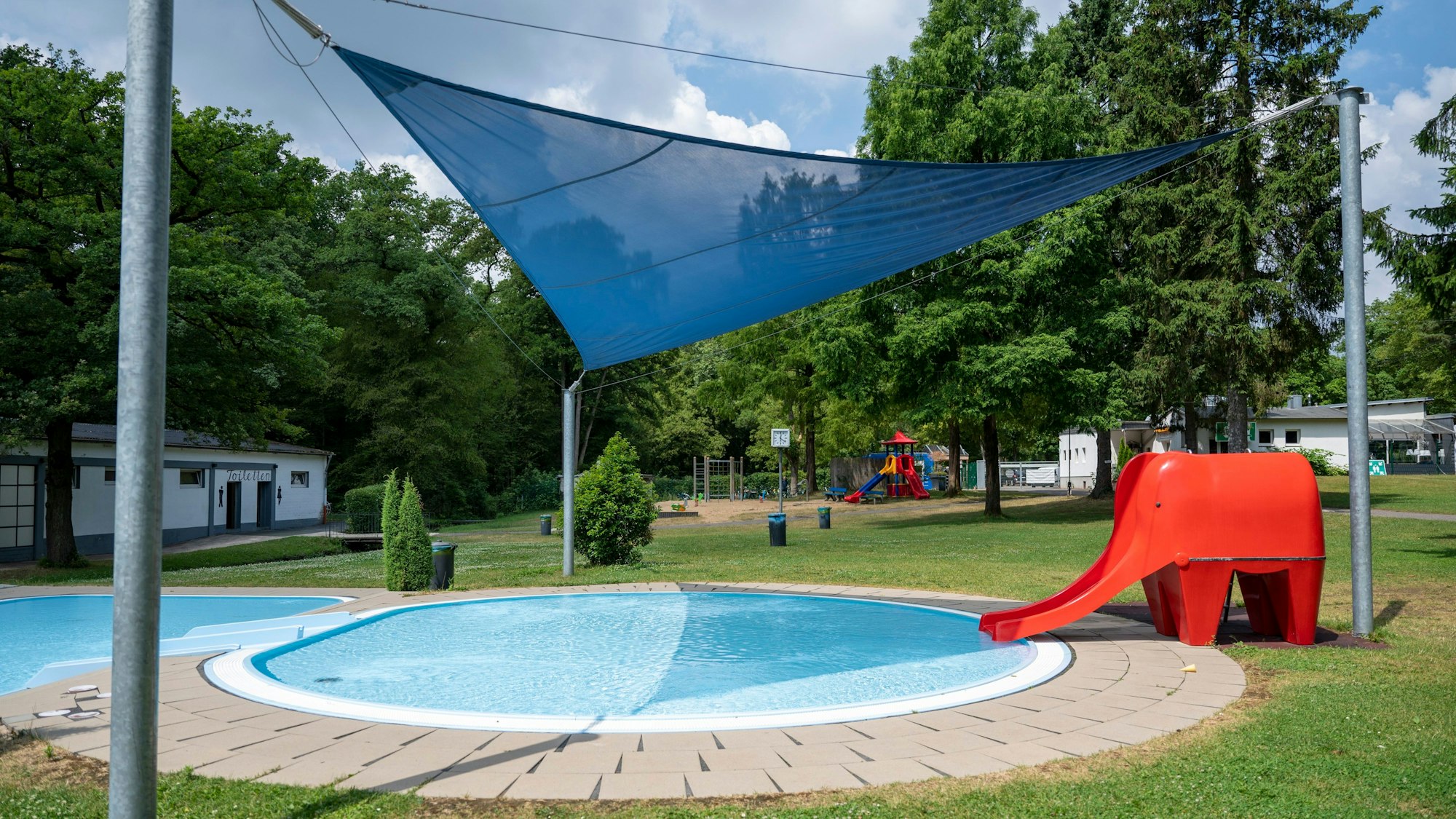Im Waldbad ist ein Kinderbecken mit einem Segeltuch und eine Elefantenrutsche.