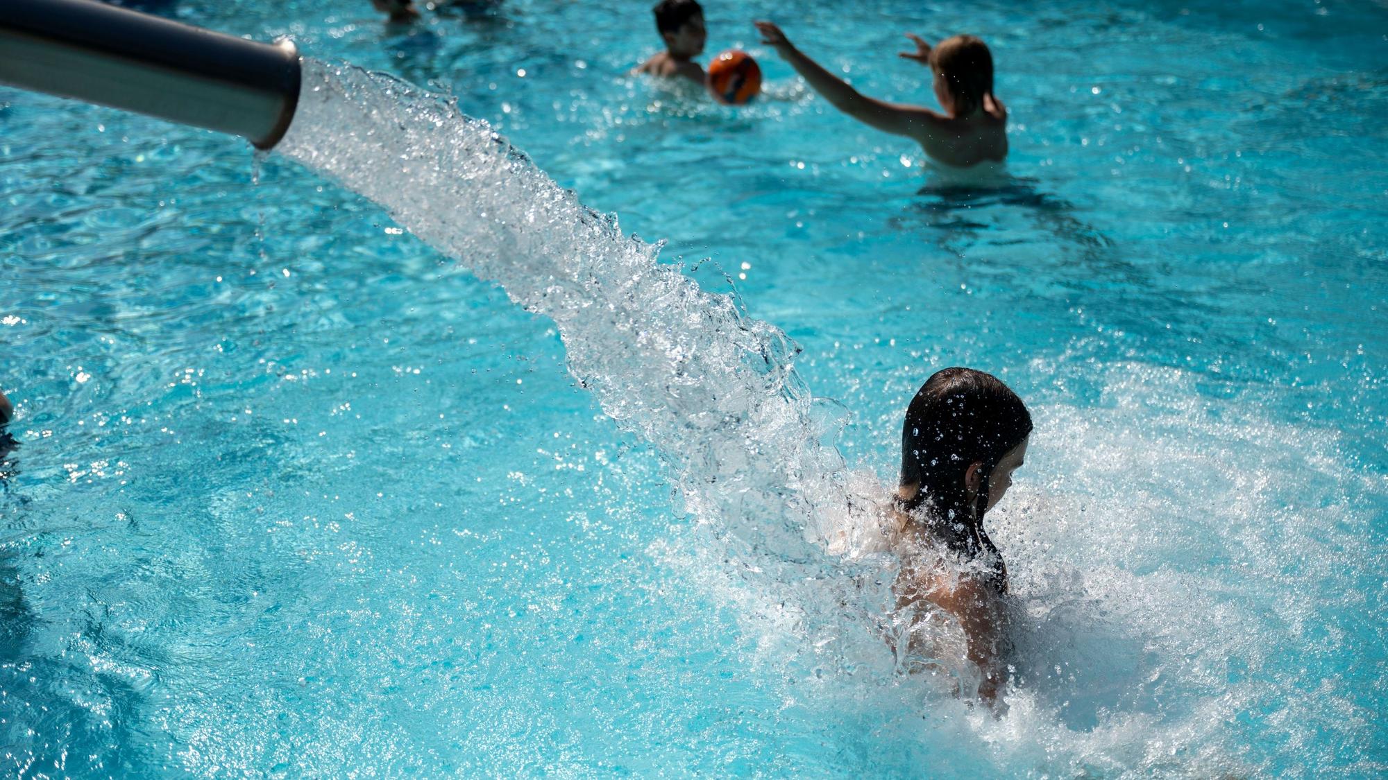 Ein Wasserstrahl schießt aus einem silbernen Rohr auf den Rücken einer jungen Frau.