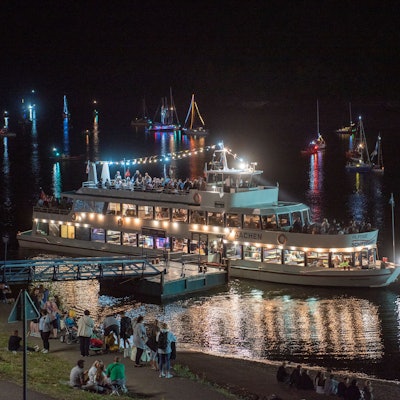 Es ist Nacht am Ufer des Rursees. Das Touristen-Schiff Stella Maris leuchtet hell auf dem Wasser.