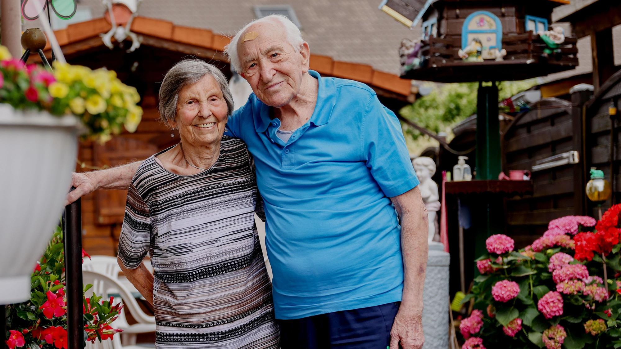 Katharina und Johann Wirotius stehen in ihrem Garten und schauen in die Kamera und freuen sich auf ihren 75. Hochzeitstag.