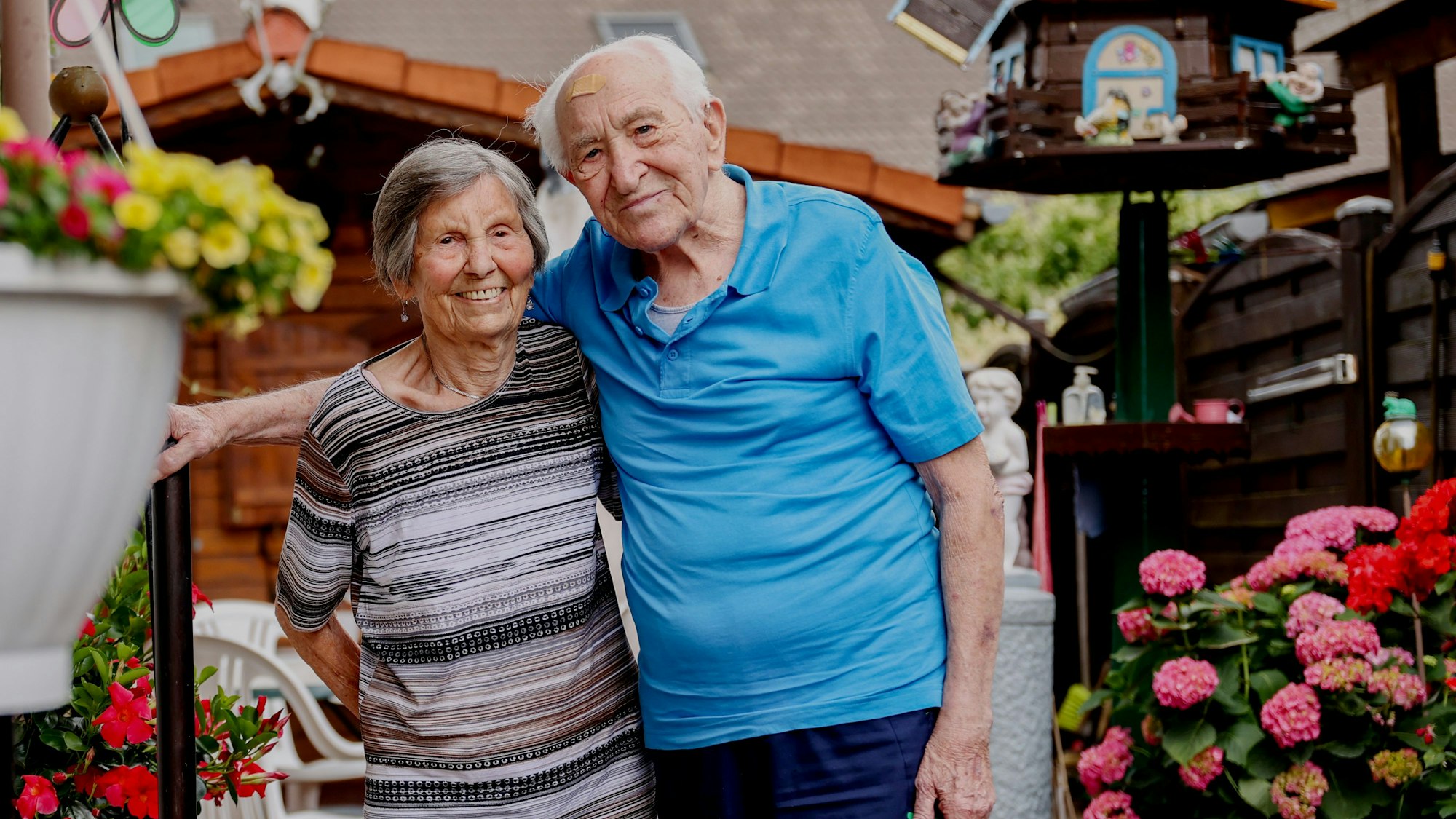 Katharina und Johann Wirotius stehen in ihrem Garten und schauen in die Kamera und freuen sich auf ihren 75. Hochzeitstag.