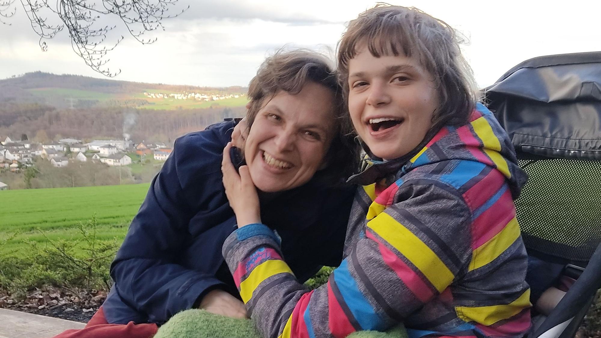 Das Bild zeigt Mutter und Tochter, die sich gut gelaunt umarmen.