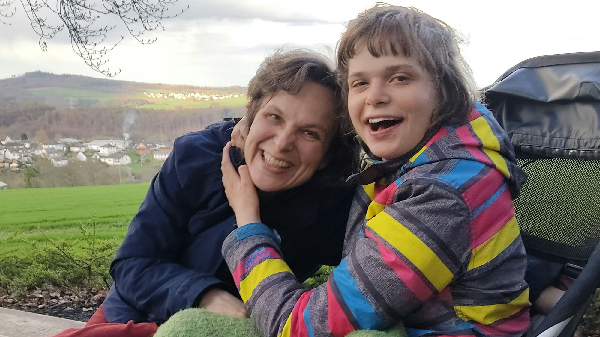 Das Bild zeigt Mutter und Tochter, die sich gut gelaunt umarmen.