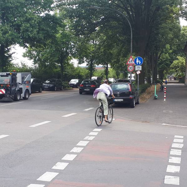 Ein Radfahrer wechselt von der Straße auf den Radfahrstreifen auf dem Gehweg.