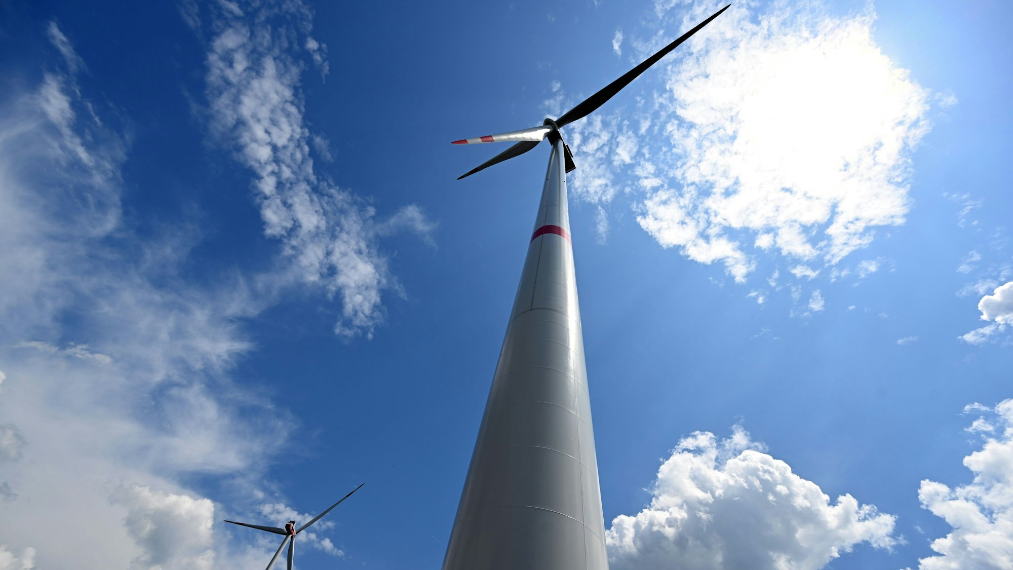Das Bild zeigt zwei Windräder vor blauem Himmel.