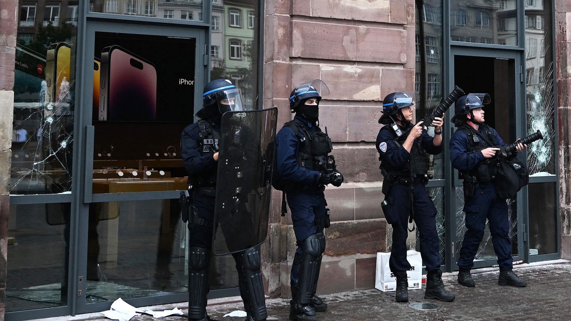 Französische Polizisten vor einem bei den Ausschreitungen beschädigten Apple-Geschäfts in Straßburg.
