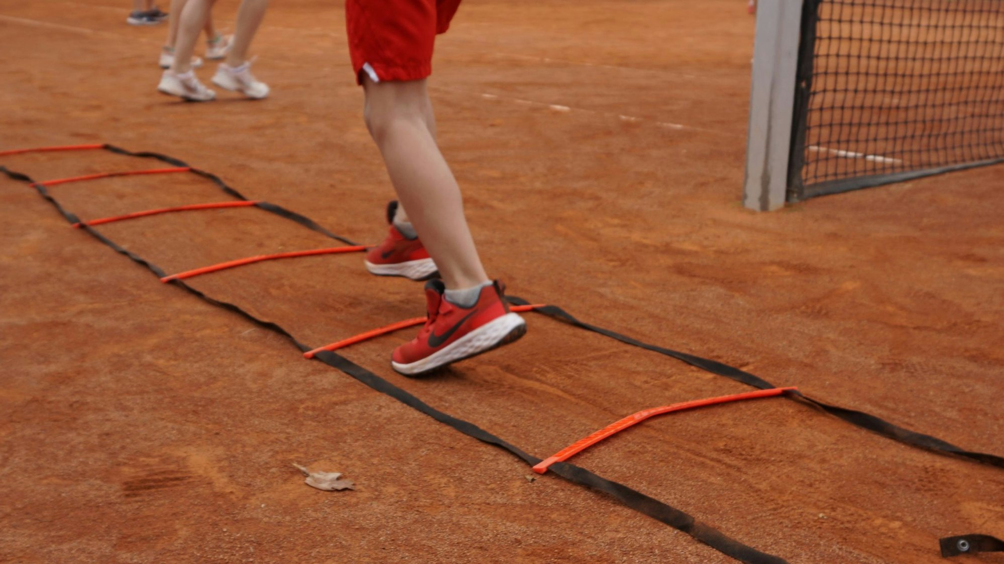 Im Bild sind die Beine eines Kindes mit roten Turnschuhen. In Trippelschritten läuft er durch ein Hindernis.