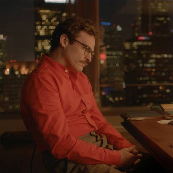 Joaquin Phoenix sitzt im Film „Her“ vor einem Computerbildschirm. Sein oranges Hemd korrespondiert mit dem orangen Hintergrundbild des Betriebssystems.