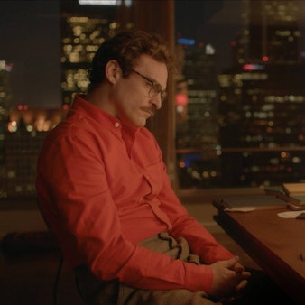 Joaquin Phoenix sitzt im Film „Her“ vor einem Computerbildschirm. Sein oranges Hemd korrespondiert mit dem orangen Hintergrundbild des Betriebssystems.