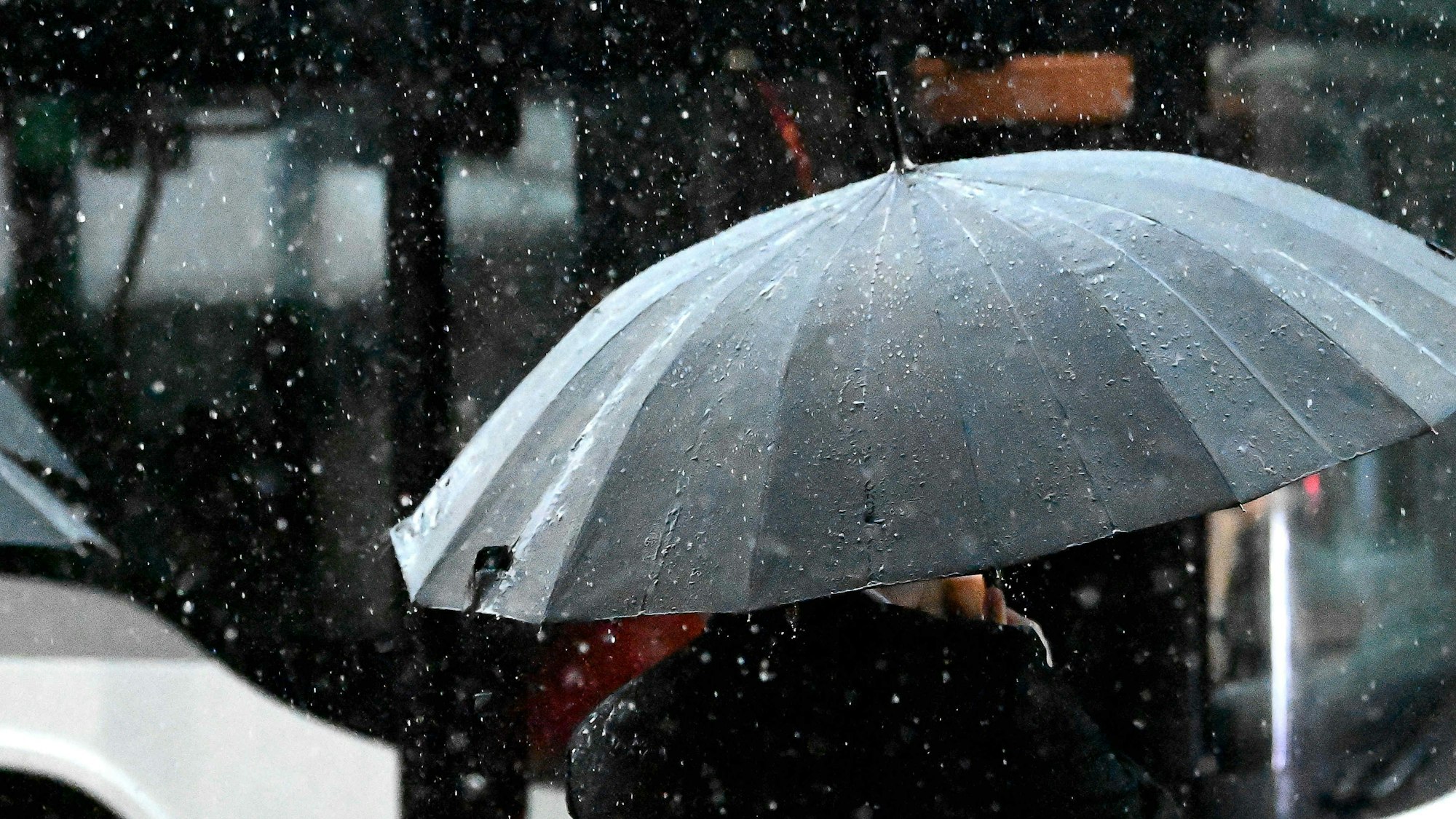 Regen prasselt auf einen Regenschirm.