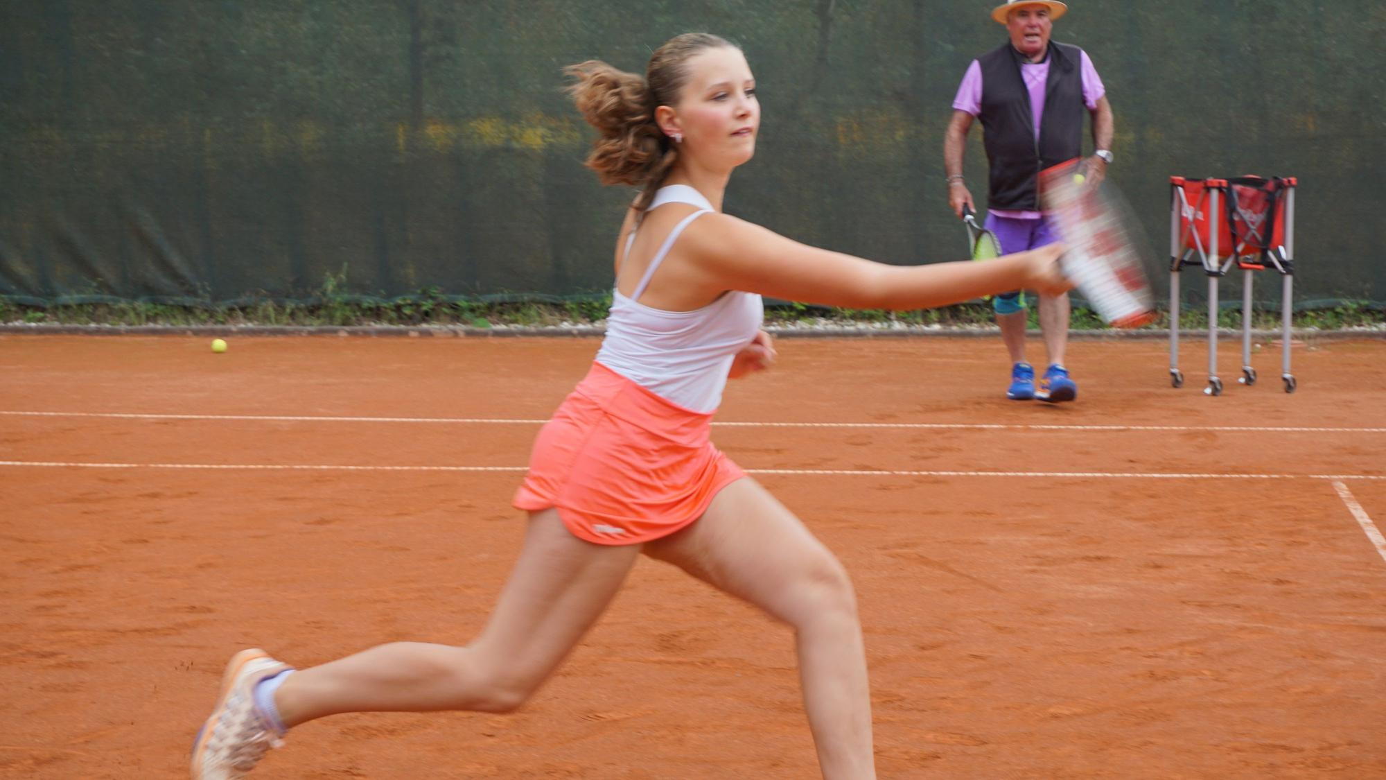 Ein Mädchen rennt über den Tennisplatz.
