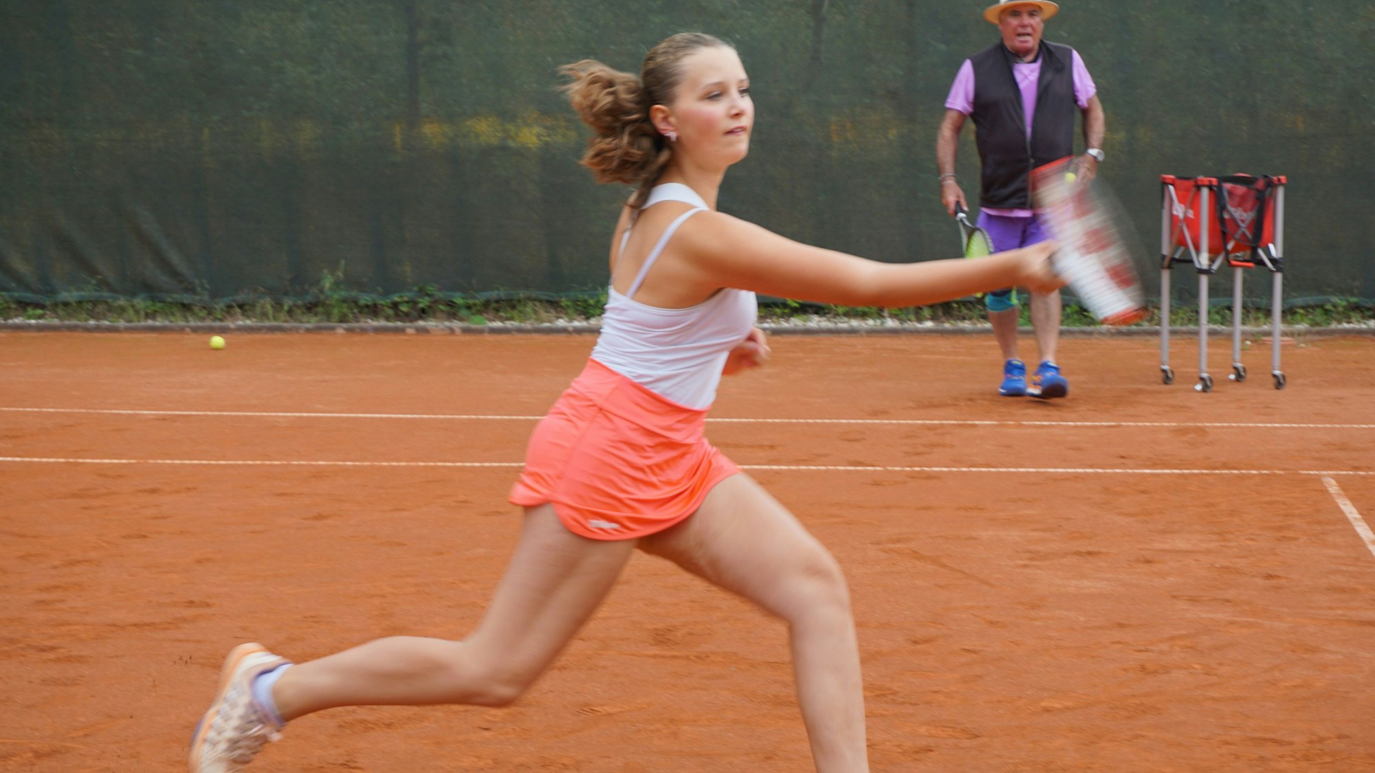 Ein Mädchen rennt über den Tennisplatz.