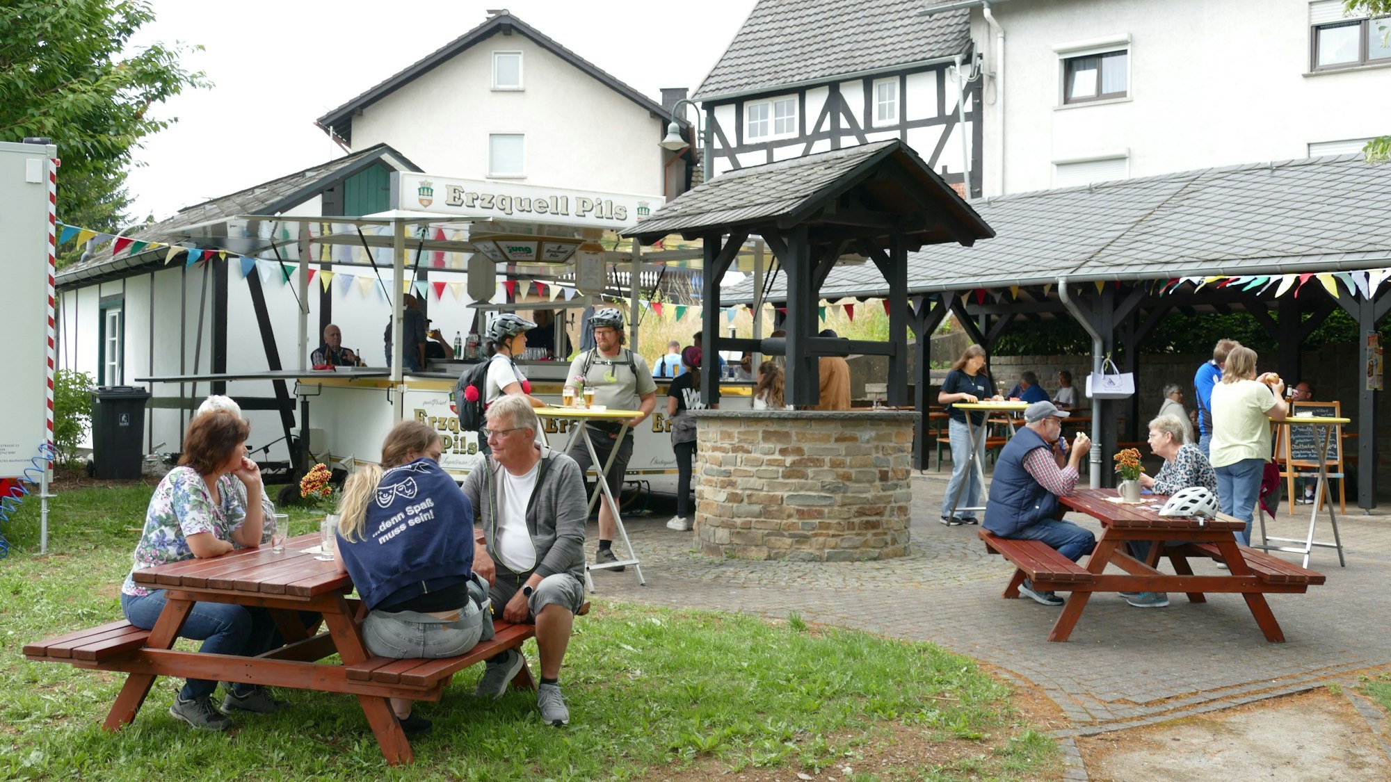 Menschen sitzen bei einer Rast auf Bänken.