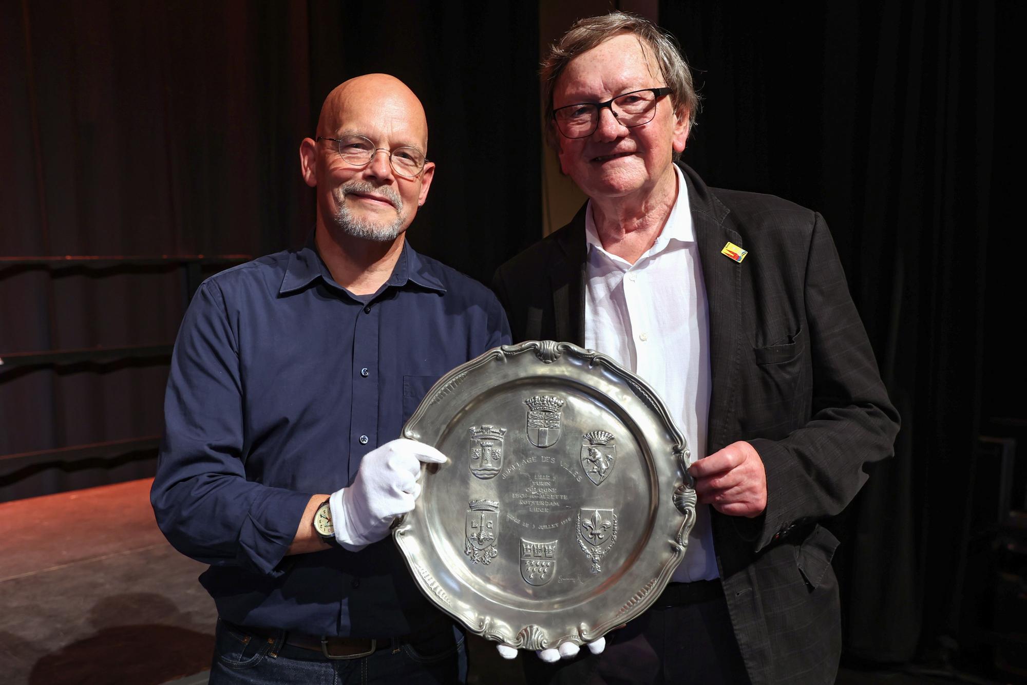 Volker Thiel von dem Haus der Geschichte und Hemann Jakob vom Freundeskreis Köln-Turin Foto halten den Zinnteller, der an den Gründungstag der Ringpartnerschaft erinnert, in den Händen.