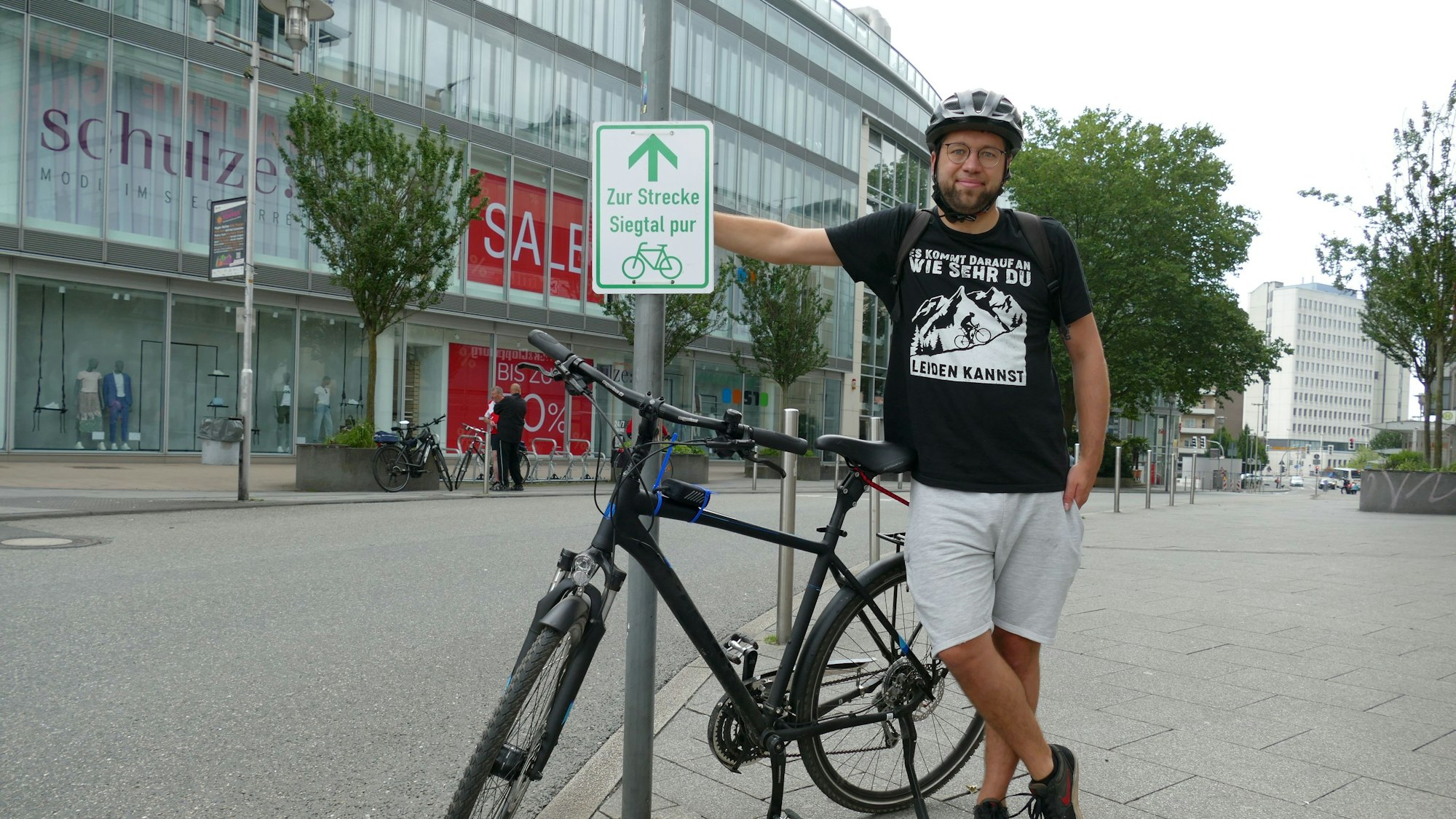 Ein Mann mit Fahrradhelm steht neben seinem Fahrrad.