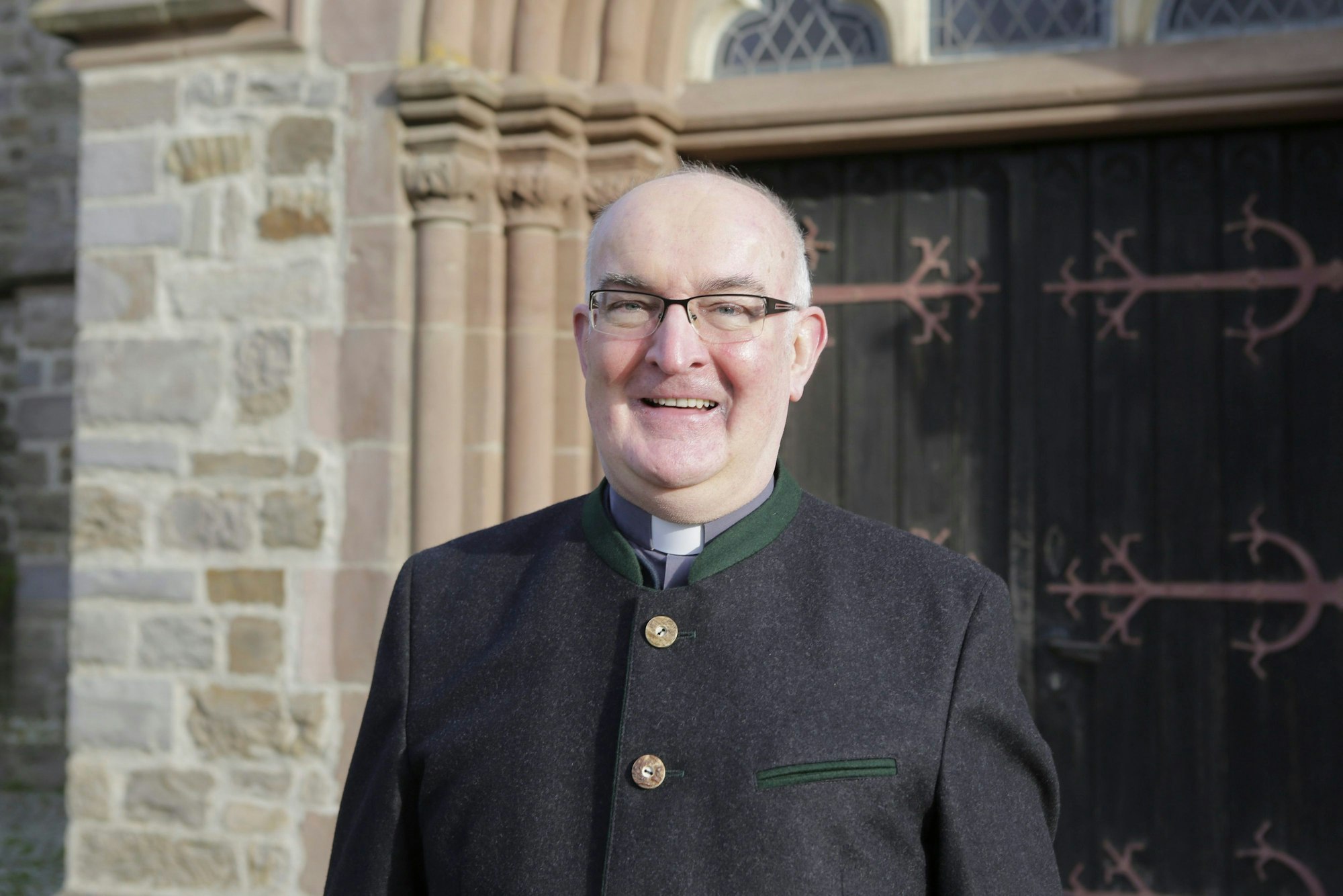 Pastor Lambert Schäfer steht vor dem Portal von St. Nikolaus, der katholischen Pfarrkirche von Wipperfürth.