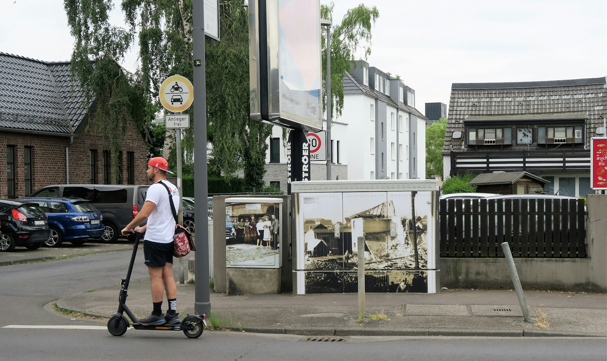 Ein historisches Motiv prangt auf einem Stromkasten. Ein Mann auf einem Elektroroller fährt gerade daran vorbei.