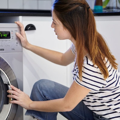Frau wäscht Wäsche mit einer Waschmaschine